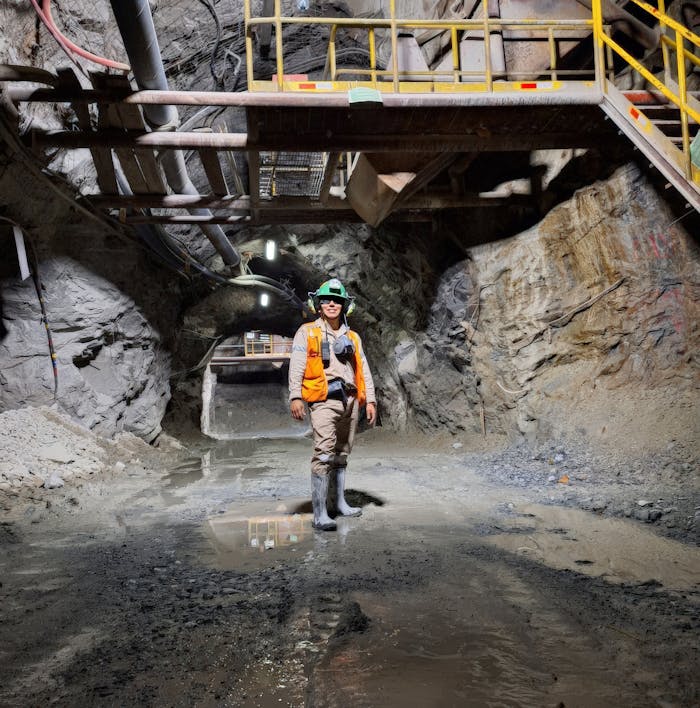 hero-img-01 Engineer standing in an illuminated underground mine tunnel, showcasing mining safety gear and modern infrastructure.