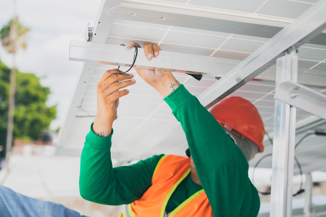 about-01 A solar technician in PPE installs a solar panel, showcasing renewable energy work.